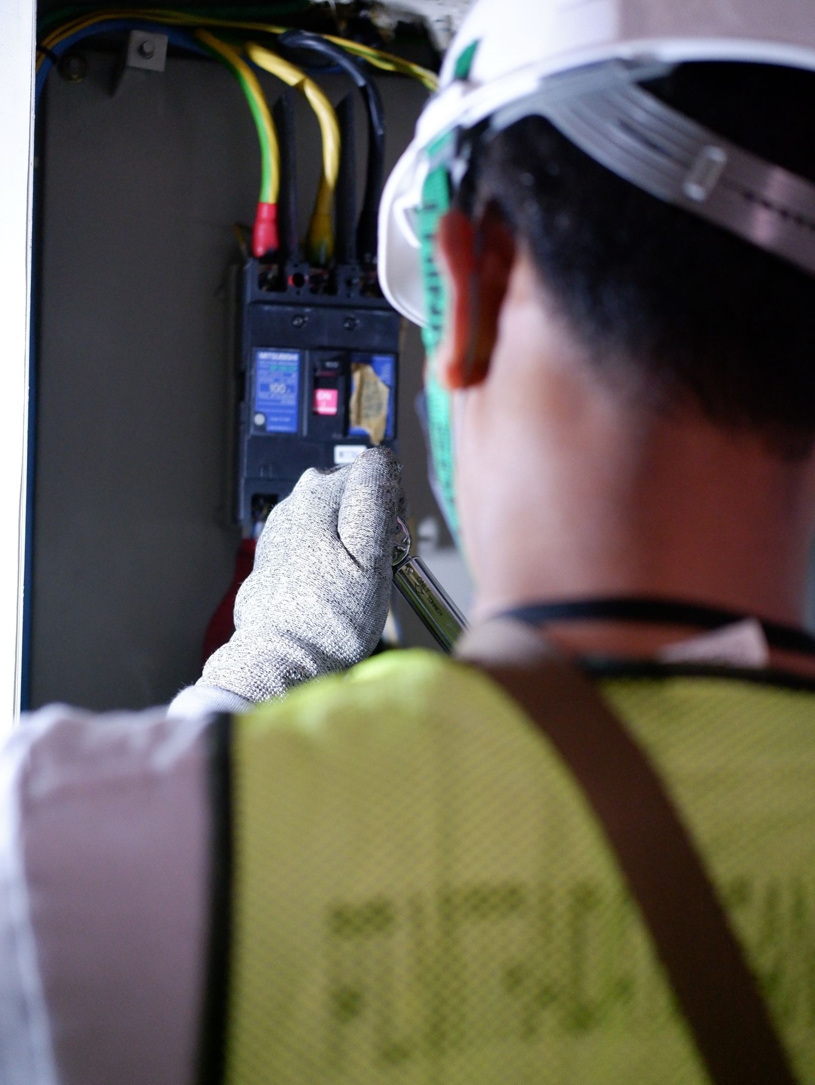 Electricista trabajando con guantes en un tablero eléctrico durante una instalación