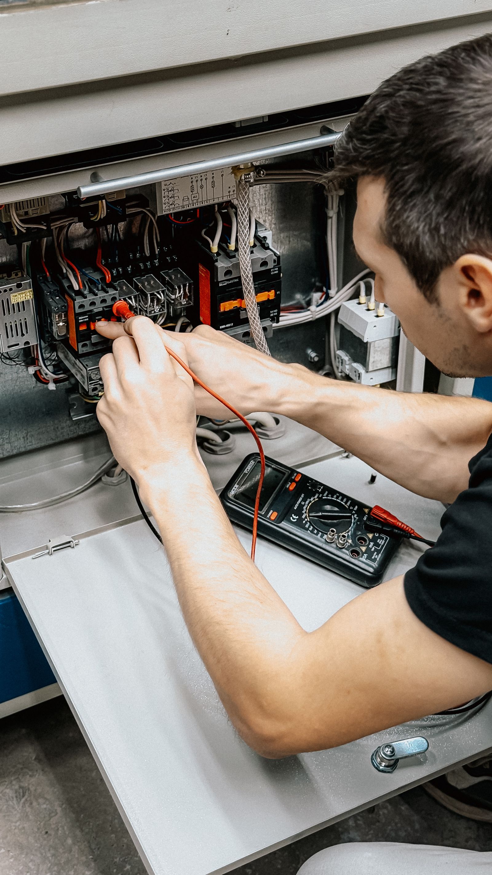 Electricista midiendo con un multímetro en un tablero eléctrico