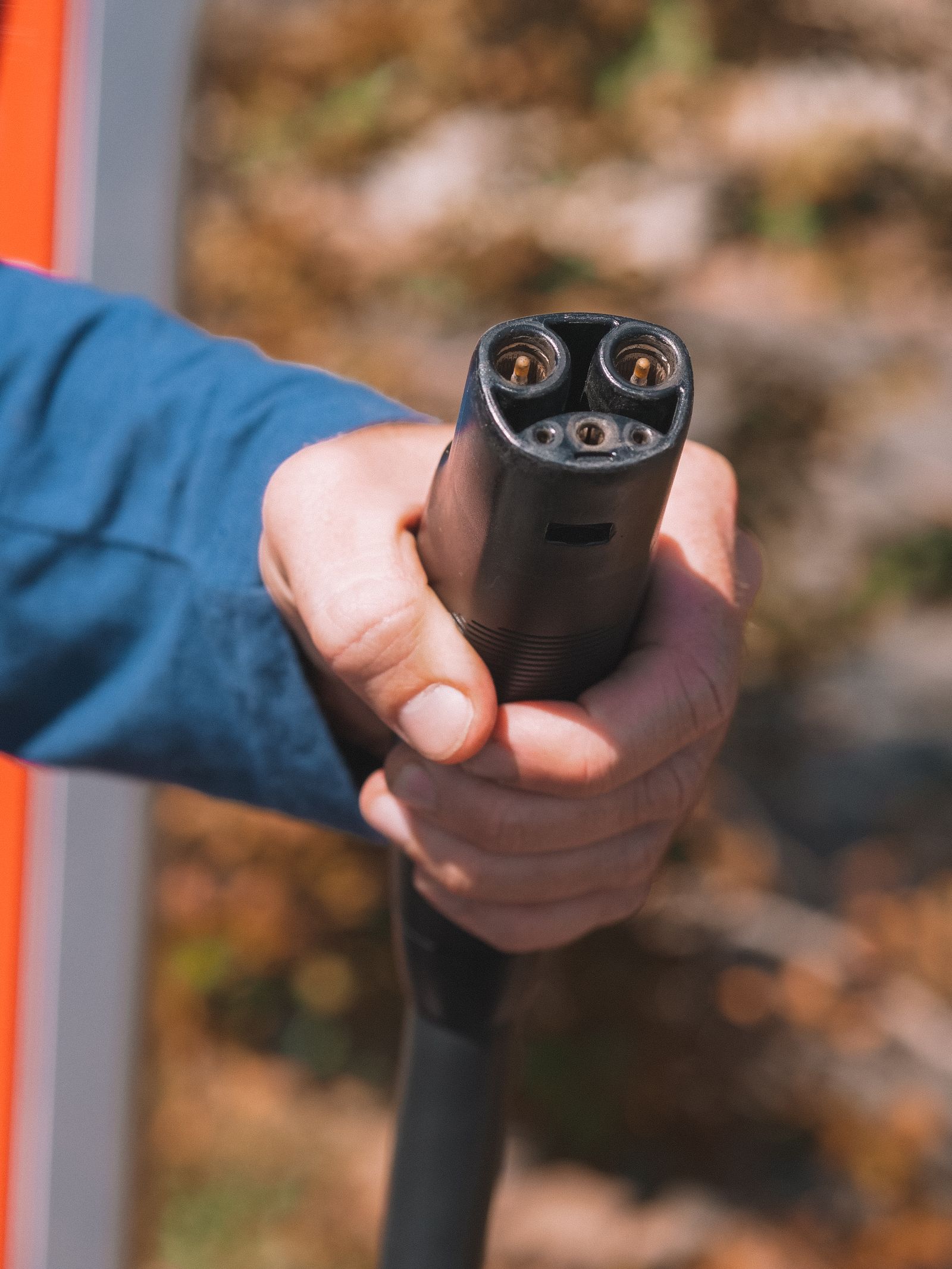 Mano sosteniendo el conector de carga de un auto eléctrico