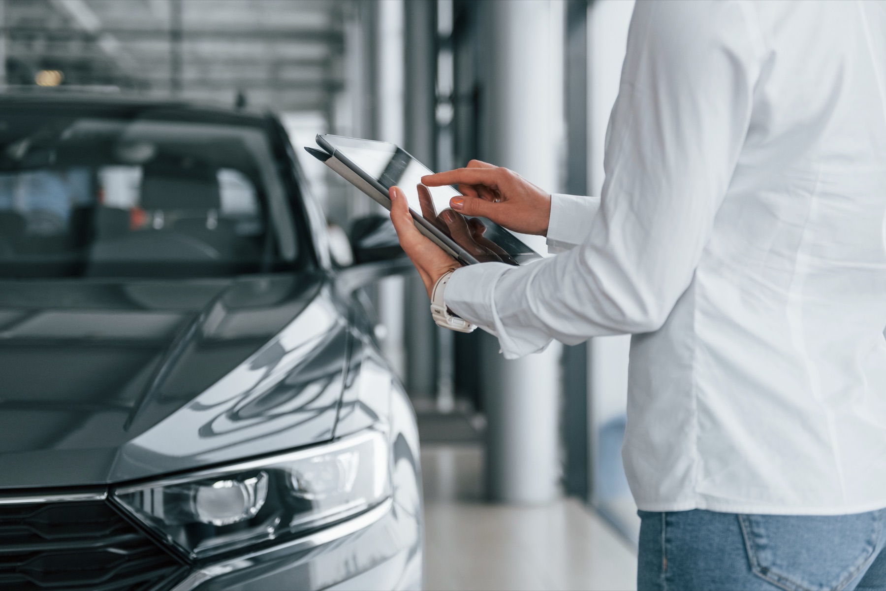 Persona revisando los datos de un auto con una tablet antes de comprarlo