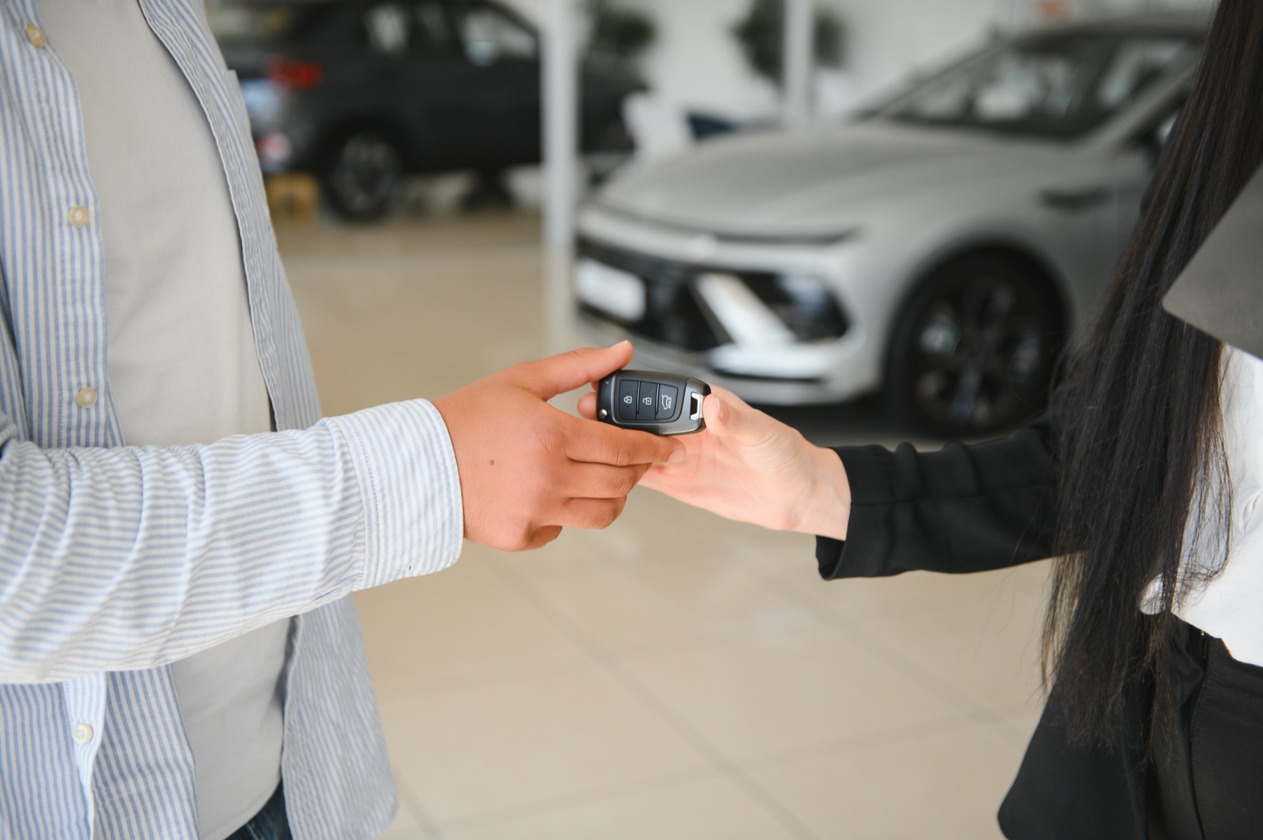 Vendedora entregando la llave de un auto nuevo a un cliente en un concesionario